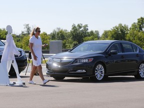 FILE - In this July 20, 2015 file photo, a pedestrian crosses in front of a vehicle as part of a demonstration at Mcity on its opening day on the University of Michigan campus in Ann Arbor, Mich. The Trump administration has quietly set aside plans to require new cars to be able to wirelessly talk to each other, auto industry officials said, jeopardizing one of the most promising technologies for preventing traffic deaths. (AP Photo/Paul Sancya, File)