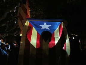 A man holds a 'Estelada', the pro-independence Catalan flag, as demonstrators gather outside the Catalonian Parliament to protest against the decision of a judge to jail ex-members of the Catalan government, in Barcelona, Spain, Thursday, Nov. 2, 2017. A Spanish judge has ordered nine ex-members of the government in Catalonia jailed while they are investigated on possible charges of sedition, rebellion and embezzlement. (AP Photo/Manu Fernandez)