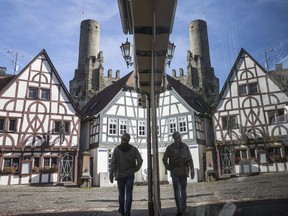 A passerby  is reflected by a glass pane, right, as he walks through the historic inner city, of Eppstein, Germany, Wednesday, Nov. 1, 2017.  (Frank Rumpenhorst/dpa via AP)