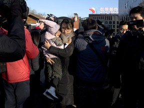 A woman leaves with a child after telling the media she came to withdraw the child from the RYB kindergarten in Beijing, China, Friday, Nov. 24, 2017. Chinese authorities are investigating allegations that children attending the RYB kindergarten in Beijing run by a U.S.-listed company have been abused and molested. (AP Photo/Ng Han Guan)