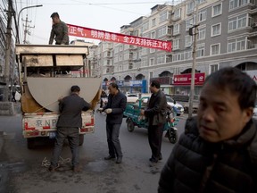 Workers load kitchen equipment near propaganda slogans at left that read: "Carry forward righteousness, Differentiate right and wrong, Fully support eviction work" onto a truck from a restaurant that's closed by the eviction in the outskirts of Beijing Monday, Nov. 27, 2017. Authorities in Beijing have been evicting domestic migrant workers from the capital in droves, triggering a public outcry over the harsh treatment of people the city depends on to build their skyscrapers, care for their children and take on other lowly-paid work. (AP Photo/Ng Han Guan)