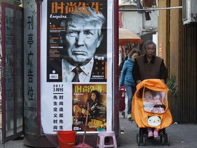 In this Wednesday, March 15, 2017, file photo, a man pushes a stroller past a magazine advertisement featuring U.S. President Donald Trump at a newsstand in Shanghai, China. President Donald Trump's agenda in Beijing is expected to be led by the standoff over North Korea's nuclear weapons and demands that China do more to balance trade with America. (Chinatopix Via AP, File)