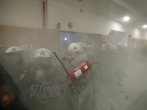 Protesters throw a fire extinguisher at riot police who guard the entrance of a court room in Athens, Wednesday, Nov. 29, 2017. Protesters clashed with police at the Athens court of appeals as foreclosures begin anew as part of reforms under Greece's bailout plans. (AP Photo/Thanassis Stavrakis)