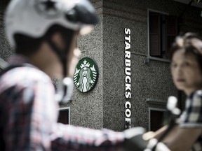 Motorists ride past a Starbucks Corp. coffee shop in Shanghai, China.