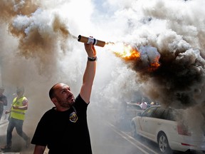 In this June 29, 2017 file photo, a protestor burns a flare during a taxi strike and protest against companies such as Uber and Cabify in Barcelona, Spain. The European Union's top court has ruled on Wednesday Dec. 20, 2017 that ride-hailing service Uber should be regulated like a taxi company, a decision that could change the way it functions across the continent.