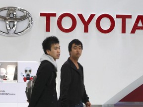 FILE - In this Nov. 13, 2017, file photo, visitors walk through a Toyota showroom in Tokyo. Toyota Motor Corp. says it sold 10.35 million vehicles around the world this year, up 2 percent from the previous year, and predicts higher sales next year.