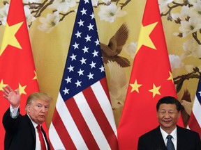 FILE - In this Thursday, Nov. 9, 2017, file photo, U.S. President Donald Trump waves next to Chinese President Xi Jinping after attending a joint press conference at the Great Hall of the People in Beijing. China's main official news agency is warning U.S.-Chinese relations will face "more pressure and challenges" following President Donald Trump's decision to label Beijing a rival.