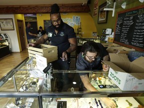 Retail clerks Akira Jones, left, and Kris Tibbetts, right, restock a display case of glass marijuana pipes at Cannabis City, Tuesday, July 7, 2015, in Seattle.