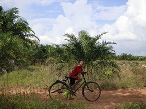 In this June 12, 2017 photo, a villager stands with his bicycle on land they fear will be affected by Asia Pulp & Paper expansion in West Bangka, Indonesia. The pulp and paper company part of the Indonesian conglomerate Sinarmas denies it controls a little-known plantation company it wants as a supplier but an Associated Press investigation reveals the paper giant has had close ties to the company, as it does with more than two dozen other suppliers it characterizes as independent.