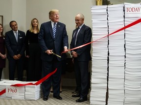 President Donald Trump cuts a ribbon during an event on federal regulations in the Roosevelt Room of the White House, Thursday, Dec. 14, 2017, in Washington.