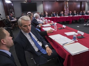 Sen. Rob Portman, R-Ohio, a member of the tax-writing Senate Finance Committee, confers with an aide as tax bill conferees gather to work on the sweeping GOP plan, on Capitol Hill in Washington, Wednesday, Dec. 13, 2017.