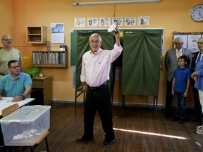 Former Chilean President and current presidential candidate Sebastian Pinera raises his ballot before cast his vote during presidential elections runoff in Santiago, Chile, Sunday, Dec. 17, 2017. Chileans voters will decide Sunday whether to swing the world's top copper-producing country to the right or maintain its center-left path in a fiercely contested presidential runoff election.