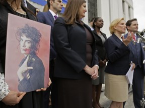 FILE - In this May 16, 2017 file photo, Leisa Askew holds a photograph of her daughter, Cash Askew, who died in the Ghost Ship warehouse fire, as attorney Mary Alexander, second from right, speaks during a news conference Tuesday, May 16, 2017, after the filing of a wrongful death lawsuit in Oakland, Calif. The one-year anniversary of the deadliest building fire in the U.S. in more than a decade is bringing back painful memories for victims' families. "You never recover from it," said Alexander, an attorney who is representing many victims' families in a lawsuit that names the city, the warehouse's owner and its operator. "All of them are anxious about the one-year. It's creating a lot of emotions." (AP Photo/Eric Risberg, File)