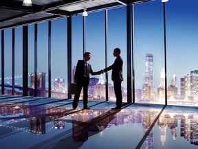 Multi-Ethnic Businessmen Shaking Hands Indoors With City As A Background