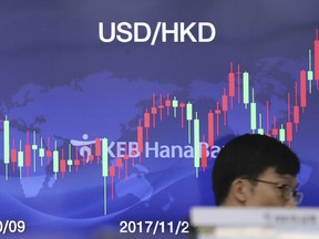 A currency trader walks by the screen showing the foreign exchange rate at the foreign exchange dealing room in Seoul, South Korea, Friday, Dec. 29, 2017. Asian stock markets mostly drifted higher on Friday after Wall Street finished with modest gains.