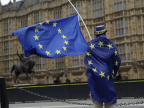 A Pro-EU membership supporter holds European Union flags as he protests against Brexit across the street from the Houses of Parliament in London in London, Tuesday, Dec. 5, 2017. British Prime Minister Theresa May's government was holding talks Tuesday with the Northern Irish party that props it up, in a bid to salvage a crumbling Brexit deal ahead of a deadline next week