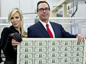 Steven Mnuchin, U.S. Treasury secretary, right, and his wife Louise Linton hold a 2017 50 subject uncut sheet of $1 dollar notes bearing Mnuchin's name for a photograph at the U.S. Bureau of Engraving and Printing in Washington, D.C., U.S., on Wednesday, Nov. 15, 2017.