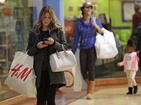 In this Thursday, Dec. 21, 2017, photo, customers carry bags as they shop for the holidays at Concord Mills mall in Concord, N.C. On Friday, Dec. 22, payment technology firm First Data said that holiday spending is surging in the days before Christmas.