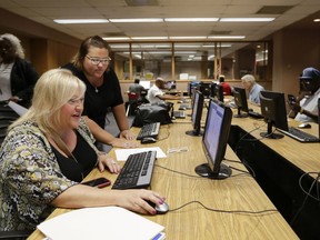 In this Thursday, July 27, 2017, photo, Cheryl Bast of Omaha, left, is accompanied by her daughter Liz Pierson as she works on an application for a position with Omaha Public Schools during a job fair held in Omaha, Neb. On Monday, Dec. 11, 2017, the  Labor Department reports on job openings and labor turnover for October.