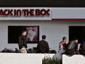 FILE - In this Feb. 17, 2008 file photo, patrons of a Jack-In-the-Box gather in its parking lot in Los Angeles.  Jack in the Box is selling the Qdoba restaurant chain to private-equity firm Apollo Global Management for $350 million in cash. The chain of Mexican restaurants has been a sore spot on Jack in the Box's overall business, posting same-store sales declines throughout 2017. The San Diego burger chain has been weighing its options with Qdoba for most of this year. The deal is expected to close by April 2018.