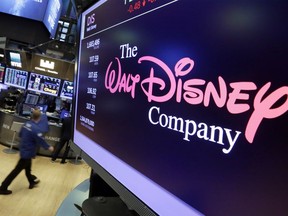 FILE - In this Aug. 8, 2017, file photo, The Walt Disney Co. logo appears on a screen above the floor of the New York Stock Exchange. Disney is buying a large part of the Murdoch family's 21st Century Fox in a $52.4 billion deal, announced Thursday, Dec. 14, including film and television studios, cable and international TV businesses as it tries to meet competition from technology companies in the entertainment business.