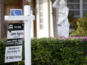 FILE - In this Thursday, Jan. 8, 2015, file photo, a "Sale Pending" placard is placed atop a realty sign outside a home for sale in Surfside, Fla. On Wednesday, Dec. 27, 2017, the National Association of Realtors releases its November report on pending home sales, which are seen as a barometer of future purchases.