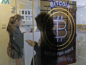 FILE - In this Friday, Dec. 8, 2017, file photo, people use a Bitcoin ATM in Hong Kong. The public's intense interest in all things bitcoin, and efforts by entrepreneurs to fund their businesses with digital currencies, has begun to draw attention from regulators.