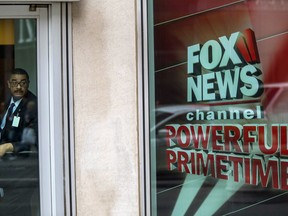 FILE - In this Wednesday, April 19, 2017, file photo, a security guard looks out of the the News Corp. headquarters in Midtown Manhattan, in New York. Disney announced Thursday, Dec. 14, 2017, that it is buying a large part of Fox, but Fox News Channel and other U.S. television businesses are staying with the Murdoch family.