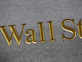 FILE - This Monday, July 6, 2015, file photo shows a sign for Wall Street carved into the side of a building in New York. World stock markets were mixed on Friday, Dec. 15, 2017, as investors waited to see if U.S. politicians could pass tax reform legislation before Christmas.