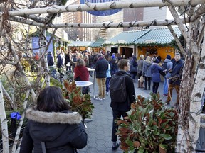 In this Thursday, Dec. 7, 2017, photo, shoppers pass through an archway into the Union Square Holiday Market in New York. At the holiday markets that pop up annually, many of the booths are staffed by artisans hoping to make a significant portion of their revenue or to get visibility that will translate into sales other times of the year.