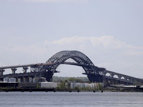File- This  May 2, 2017, file photo shows the Bayonne Bridge prior to a news conference announcing the bridge project completion, seen from Elizabeth, N.J. The elevation of the Bayonne Bridge was projected to cost about $1.3 billion before construction began more than four years ago.  This week, the Port Authority of New York and New Jersey, which owns and operates the bridge, approved allocating between $350 million and $400 million more, an overrun of more than 25 percent.