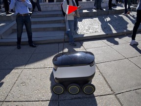 FILE - In this Feb. 20, 2017, file photo, a six-wheeled ground delivery robot, from Starship Technologies, shares the sidewalk with pedestrians at DuPont Circle in Washington, D.C. Delivery robots in San Francisco will need permits before they can roam city sidewalks under legislation approved by supervisors on Tuesday, Dec. 5, 2017.