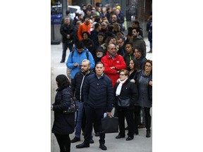 People line up outside a polling station to cast their vote for the Catalan regional election in Barcelona, Spain, Thursday, Dec. 21, 2017. Catalans are choosing new political leaders in a highly contested election called by central authorities to quell a separatist bid in Spain's northeastern region.