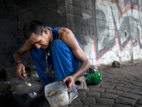 Darwin, a 40-year-old homeless man prepares his only meal for the day, in Caracas, Venezuela, Tuesday, Nov. 14, 2017. Darwin who is unemployed said he lost his house six months ago and now has to live under a bridge.
