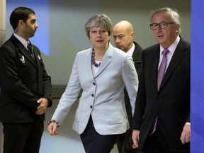 British Prime Minister Theresa May, left, walks with European Commission President Jean-Claude Juncker, right, prior to a meeting at EU headquarters in Brussels on Friday, Dec. 8, 2017.