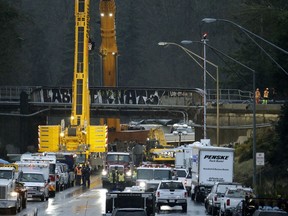 Work continues to remove damaged train cars at the scene of Monday's fatal Amtrak train crash onto Interstate 5, Tuesday, Dec. 19, 2017, in DuPont, Wash.  The Amtrak train that plunged off an overpass south of Seattle was hurtling 50 mph over the speed limit when it jumped the track, federal investigators said.