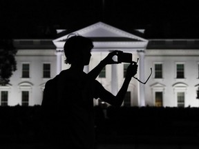 FILE - In this Aug. 25, 2017, file photo, a tourist takes a photo from Pennsylvania Avenue of the illuminated White House in Washington. The White House is embarking on a major campaign to turn public opinion against the nation's largely family-based immigration system ahead of an all-out push next year to move toward a more merit-based structure.