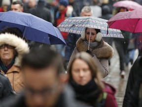 Shoppers make their way along Oxford Street in London wrapped up against the weather as snow falls Sunday, Dec. 10, 2017.