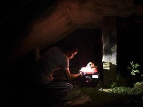 FILE - In this Dec. 21, 2017 filw photo, barrio Patron resident Karina Santiago Gonzalez works on a small power plant in Morovis, Puerto Rico. Puerto Rico authorities said on Friday Dec. 29, that nearly half of power customers in the U.S. territory still lack electricity more than three months after Hurricane Maria.