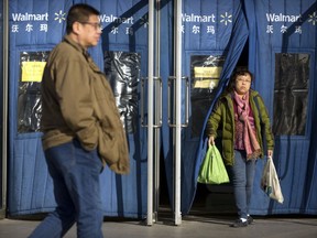 A shopper carries grocery bags as she exits a Walmart store in Beijing, Wednesday, Dec. 6, 2017. U.S. companies in China are seeing their sales improve but are frustrated by policies and regulatory barriers that block better access to the country's lucrative market, according to a survey released Wednesday.