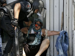 A police officer helps a demonstrator remove herself from clashes during a general strike against a pension reform measure outside Congress in Buenos Aires, Argentina, Monday, Dec. 18, 2017. Union leaders complain the legislation, which already passed in the Senate, would cut pension and retirement payments as well as aid for some of poor families.