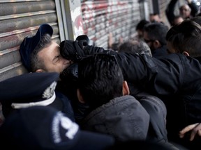 A police officer guarding the main entrance of the Labor ministry is punched by a protester as Communist-backed unionists try to enter the building during a protest in central Athens, Tuesday, Dec 5, 2017. The protesters invaded the ministry as they were demonstrating against proposals to amend a law regarding strikes.