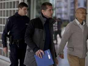 A police officer escorts Alexander Vinnik, center, as they arrive at Greece's supreme court in Athens, on Wednesday, Dec. 6, 2017. Greece's Supreme Court holds an extradition hearing for Russian cybercrime suspect Alexander Vinnik, wanted in the United States on charges of laundering billions of dollars' worth of bitcoin.