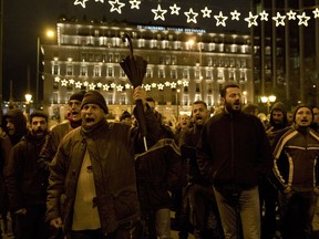 Supporters of the communist-affiliated union PAME shout slogans outside the Greek parliament as they protest in central Athens on Thursday, Dec. 21, 2017. The demonstration was organized against draft legislation that would impose tougher restriction against anti-bailout protesters who have sought to block the auction of homes that have gone into default because their owners can't meet mortgage payments.