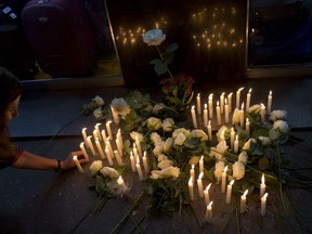 In this Nov. 21, 2017 photo, a woman places a candle at the site where homeless woman Fernanda Rodrigues dos Santos was killed in Copacabana, Rio de Janeiro, Brazil. Police say 24-year-old Rodrigo Gomes Rodrigues, a medical student who lives in the neighborhood, has confessed to the killing.