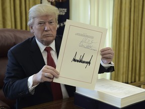 This file photo taken on December 22, 2017 shows U.S. President Donald J. Trump holding up a document during an event to sign the Tax Cut and Reform Bill in the Oval Office at The White House in Washington, D.C.