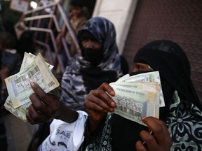 FILE - In this Nov. 14, 2015 file photo, women display paper currency after receiving cash support from UNICEF, in Sanaa, Yemen. Saudi Arabia's King Salman has ordered the transfer of $2 billion to Yemen, a day after the war-torn country's Saudi-backed prime minister called on the kingdom and its allies to save the local currency from "complete collapse." Saudi Arabia said in a statement on Wednesday, Jan. 17, 2018, that funds would be deposited in Yemen's Central Bank to help address the "deteriorating economic situation faced by the Yemeni people."