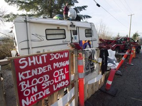 A protester who goes by the name Uni stands on top of a trailer outside the main gates of Kinder Morgan in Burnaby, B.C., Wednesday, Jan. 10, 2018. Municipalities and residents in British Columbia are set to argue that the proposed route of the Trans Mountain pipeline expansion would damage sensitive ecosystems, harm public parks and trails and adversely impact homeowners.THE CANADIAN PRESS/Jonathan Hayward