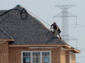 A construction worker shingles the roof of a new home in a development in Ottawa on July 6, 2015.