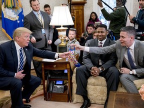 President Donald Trump is handed a pair of Aflac socks by Michael Porter of Columbus, Ga., right, during a meeting with American workers on the impact of the tax reform bill in the Oval Office at the White House, Wednesday, Jan. 31, 2018, in Washington.
